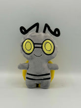 Load image into Gallery viewer, Little grey monster plush with yellow eyes and black stripes on his body. He has long thin black antenna and a yellow coin on his back!