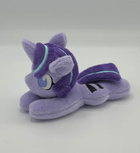 Purple horse plush laying on belly with purple star and black equals sign on flank and purple with blue stripe hair. Eye is purple.