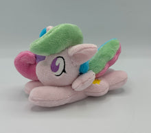 Load image into Gallery viewer, Pink horse plush laying on belly with sun on flank and blue/pink/purple/green hair. Eye is purple.
