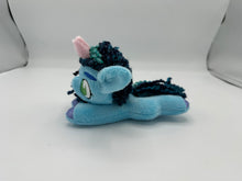 Load image into Gallery viewer, Blue horse plush laying on belly with blue yarn hair. Eye is green. Has a pink horn 
