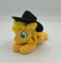Load image into Gallery viewer, Orange horse plush laying on belly with red apples on flank and yellow hair with red hair ribbons. Eye is green. Wears a brown hat.

