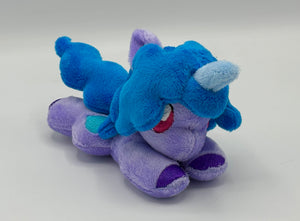 Purple horse plush laying on belly with blue heart on flank and blue hair. Eye is maroon.