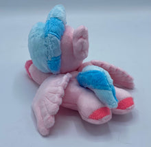 Load image into Gallery viewer, Pink hippogriff plush laying on belly. She has pink bird front feet and pink hooves on back feet. She has pink wings and a pink beak. Her eyes are purple. She has a pink ear that looks like feathers. Her hair is two tone blue. 
