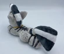 Load image into Gallery viewer, A zebra plush laying on belly. The coat is grey with black stripes. There is a grey sun design on the flank. She has a dark grey muzzle. Hair is white and grey stripes. Eye is blue. She has a gold chain around her neck. 
