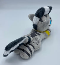 Load image into Gallery viewer, A zebra plush laying on belly. The coat is grey with black stripes. There is a grey sun design on the flank. She has a dark grey muzzle. Hair is white and grey stripes. Eye is blue. She has a gold chain around her neck. 
