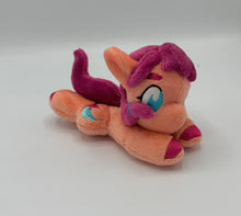 Load image into Gallery viewer, Coral colored horse plush laying on belly with pink stars and a blue trail on flank and maroon hair with blue hair tie. Eye is blue.
