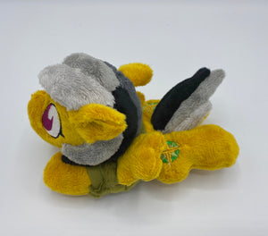 Gold colored horse plush laying on belly with green and gold compass on flank and her hair is grey shades. Eye is maroon. Wears a green shirt and safari hat