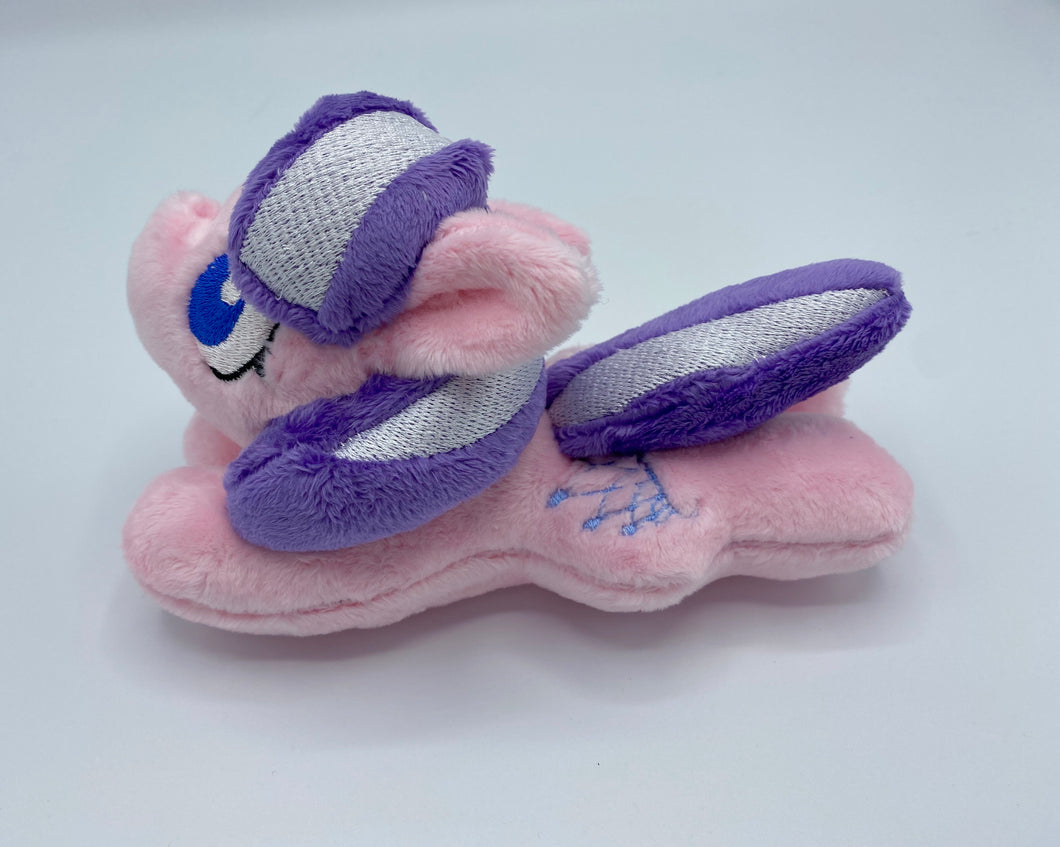 Pink horse plush laying on belly with blue tiara on flank and purple hair with white stripe. Eye is blue.