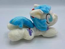 Load image into Gallery viewer, Cream horse plush laying on belly with purple hat on flank and two tone blue hair. Eye is blue. Has flower in hair. 
