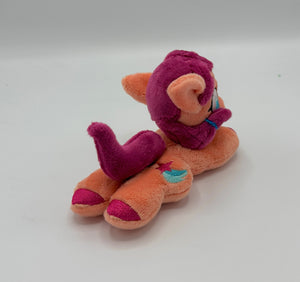 Coral colored horse plush laying on belly with pink stars and a blue trail on flank and maroon hair with blue hair tie. Eye is blue.