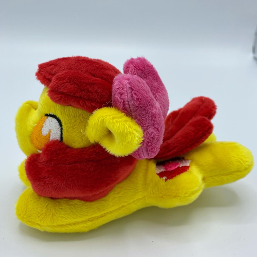 Yellow horse plush laying on belly with purple and pink crest on flank and red hair. Eye is orange. Wears a bow