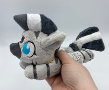 Load image into Gallery viewer, A zebra plush laying on belly. The coat is grey with black stripes. There is a grey sun design on the flank. She has a dark grey muzzle. Hair is white and grey stripes. Eye is blue. She has a gold chain around her neck. 
