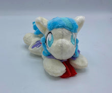 Load image into Gallery viewer, Cream horse plush laying on belly with purple hat on flank and two tone blue hair. Eye is blue. Has flower in hair. 
