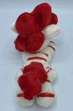 Load image into Gallery viewer, Cream colored horse plush with red stripes laying on belly with red candy canes shaped like a heart on flank and red hair. Eye is pink.
